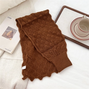 Detailed knit texture of dark brown fish scale pattern scarf on a cozy white background