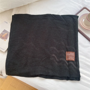 Détail d'une écharpe en laine noire montrant la texture épaisse et l'étiquette tissée