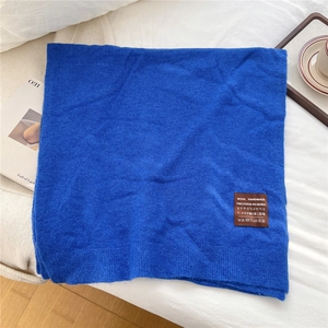 Détail de l'écharpe en maille bleu Klein avec bords côtelés et étiquette faite à la main