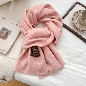 Gros plan détaillé de l'écharpe en tricot rose doux avec une étiquette de marque marron