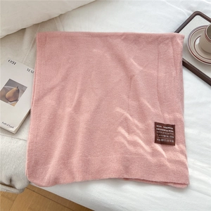 Détail de l'écharpe en laine rose montrant la texture du tricot et l'étiquette