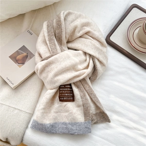Close-up of cream knit scarf with wool fabric detail, color block edges and artisan label
