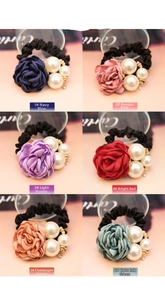 Detail of six colorful camellia flower hair ties with pearls and elastic bands
