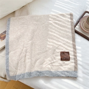 Detail of wool handmade beige scarf with contrast piping and luxury fabric label