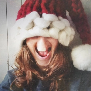 Close-up of a handmade red and white chunky knit Christmas hat with a large pompom