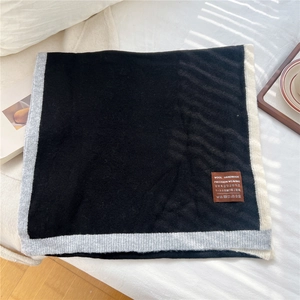 Detail of knit wool scarf featuring tricolor borders and a premium leather brand patch
