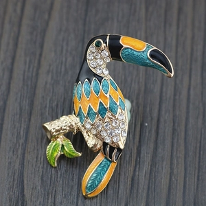 Macro detail of a toucan brooch featuring colorful enamel and sparkling rhinestones