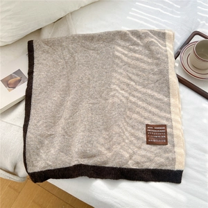 Detail of wool handmade leather label on a two-tone knitted scarf with warm texture