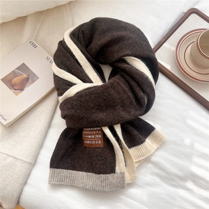 Detail of soft knit texture and contrast label on two-tone striped winter scarf