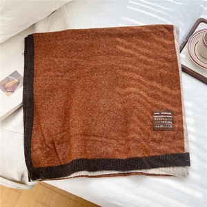 Detailed view of bicolor knit scarf texture with a woven care label on thick wool fabric