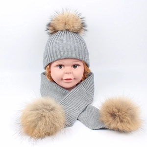 Knit baby hat and scarf set in grey featuring large fluffy raccoon fur pom-poms