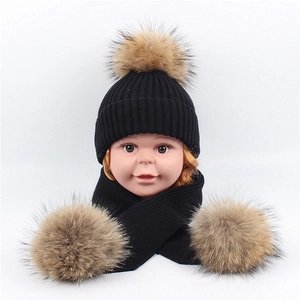 Detail of baby winter set with ribbed knit black hat and scarf featuring fluffy fur pom-poms