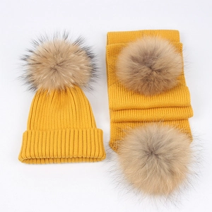 Detail of ginger knit hat and scarf set featuring soft fluffy faux fur pom-poms