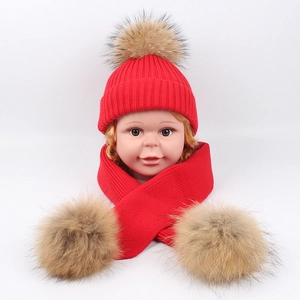 Detailed knit texture of red baby hat and scarf set with natural fur pom-poms
