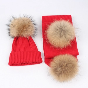 Close-up of red ribbed knit hat and scarf set with fluffy brown fur pom-poms