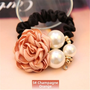 Detailed macro view of champagne orange satin rose hair tie with white pearls and crystals