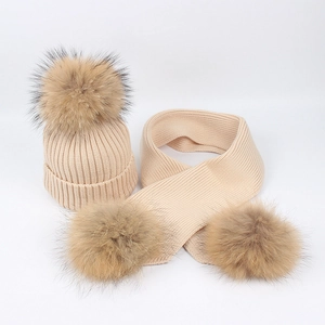 Close-up of ribbed knit texture and fluffy fur pom-poms on winter hat and scarf set