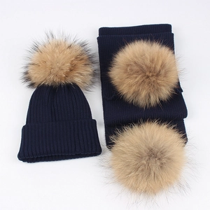 Close-up of navy knit hat and scarf set featuring soft fluffy brown faux fur pom-poms