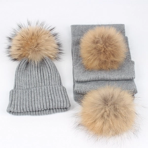 Detail of grey knitted hat and scarf set with fluffy brown faux fur pom-poms