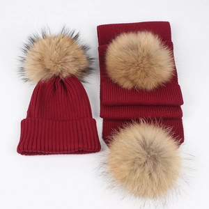 Detail of burgundy knit hat and scarf set with soft raccoon fur pom poms for winter warmth