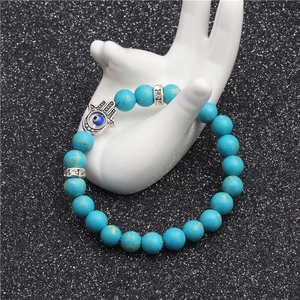 Turquoise beaded Hamsa Hand bracelet with Evil Eye charm on ceramic hand model