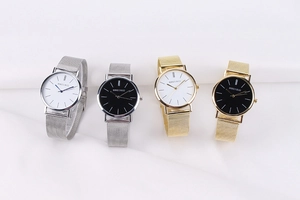 Minimalist quartz watches with silver and gold stainless steel mesh bands on white fabric