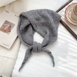 Close-up of gray knitted triangle scarf showing soft wool texture and tie-up design details