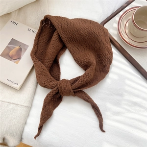 Detail of soft brown knit scarf with hollow texture on a white fabric background