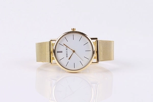 Detail of minimalist gold mesh strap quartz watch with white dial and metal case