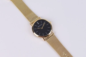 Close-up of golden mesh strap and minimalist black dial on Geneva quartz watch