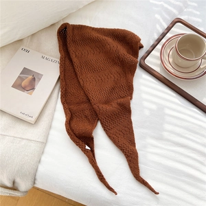 Detailed close-up of brown openwork knit triangle scarf with soft woven texture