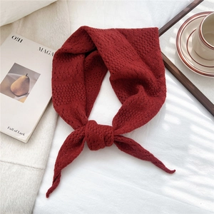 Close-up of deep red knitted triangle scarf showing fine texture and knotted design