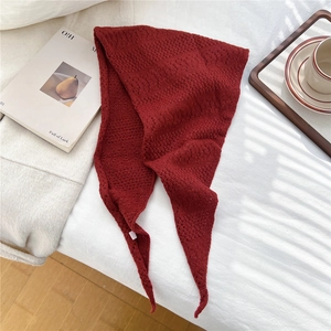 Detail of dark red knit triangle scarf featuring hollow diamond texture on soft fabric