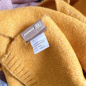 Detail view of the fabric label showing wool blend material composition on ginger knit scarf