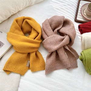 Solid color knit scarves in yellow and brown on white bedding with cozy home decor