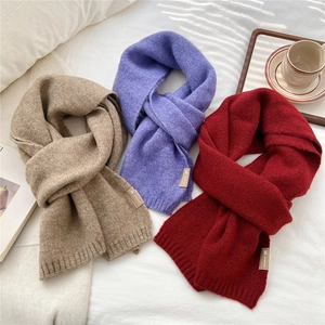 Detail of soft knit scarves in khaki, purple, and burgundy with stylish leather tags