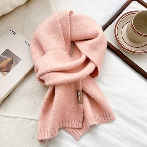 Detail of soft pink knit scarf texture with ribbed edge and elegant decorative brand tag
