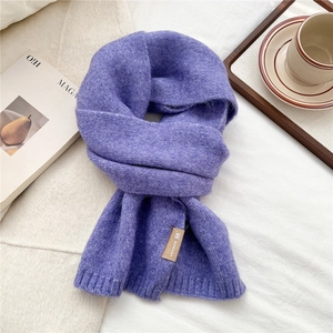 Detailed close-up of purple ribbed knit scarf texture with a stylish leather brand tag