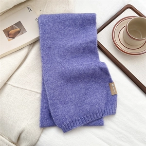 Detail of soft purple knit scarf with ribbed cuff and elegant brand label on fabric