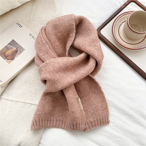 Macro detail of Morandi pink knitted scarf texture with a small decorative sewn label