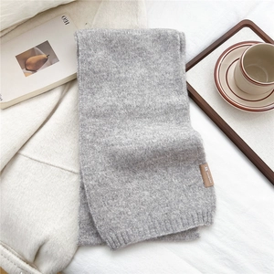 Detail of soft grey knitted scarf texture with a brown fabric brand label and casual setup