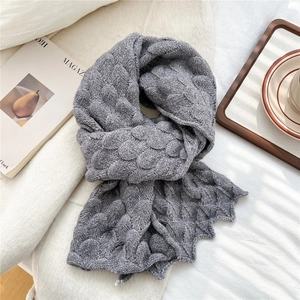 Detailed view of grey fish-scale knit scarf texture on white cozy background