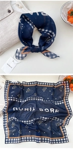 Detail of navy blue paisley square scarf with white plaid border and soft cotton feel