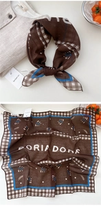 Detail view of brown paisley square scarf with navy borders and checkered patterns
