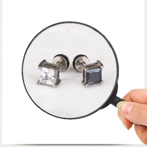 Macro close-up of square black and white zircon earrings in silver stainless steel settings