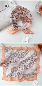 Detail of soft geometric print square scarf in warm orange and brown with fine rolled edges
