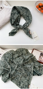 Detail view of a dark green linen silk scarf with rose patterns and DORIA DORE branding