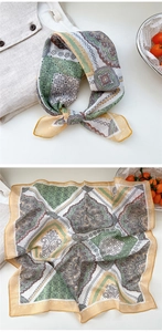 Detailed close-up of floral paisley silk scarf with green and yellow pattern on white