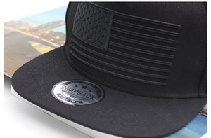 Vue détaillée de la broderie drapeau américain et sticker laser sur une casquette noire