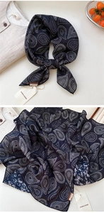 Détail d'un foulard en soie et coton à motif paisley avec étiquettes et nœud élégant